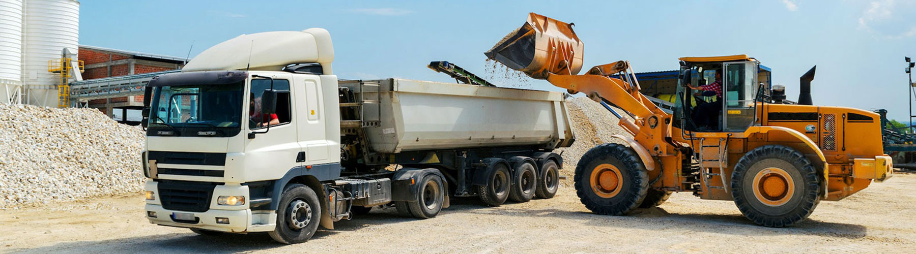 loader vehicle loading material into white cargo truck