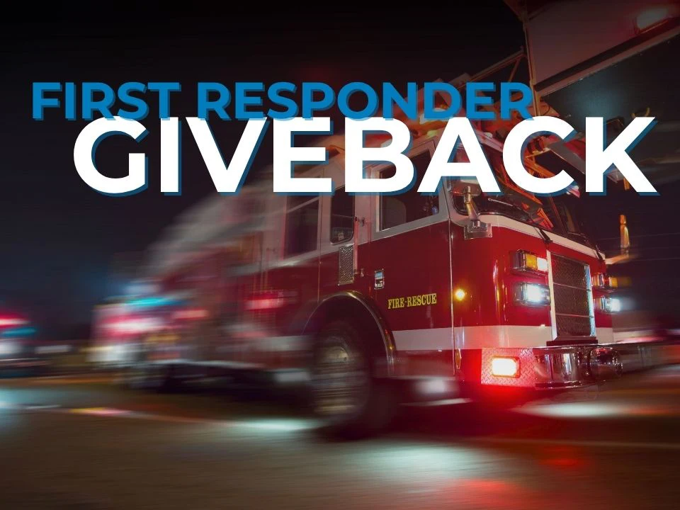 Red fire truck with sirens on with a blurred background and text of first responder giveback.