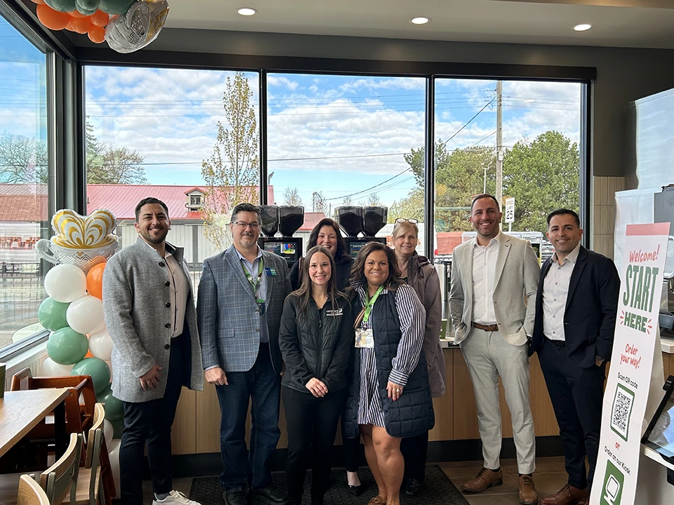 Wildfire employees smiling and celebrating with Panera Bread owners inside new location.
