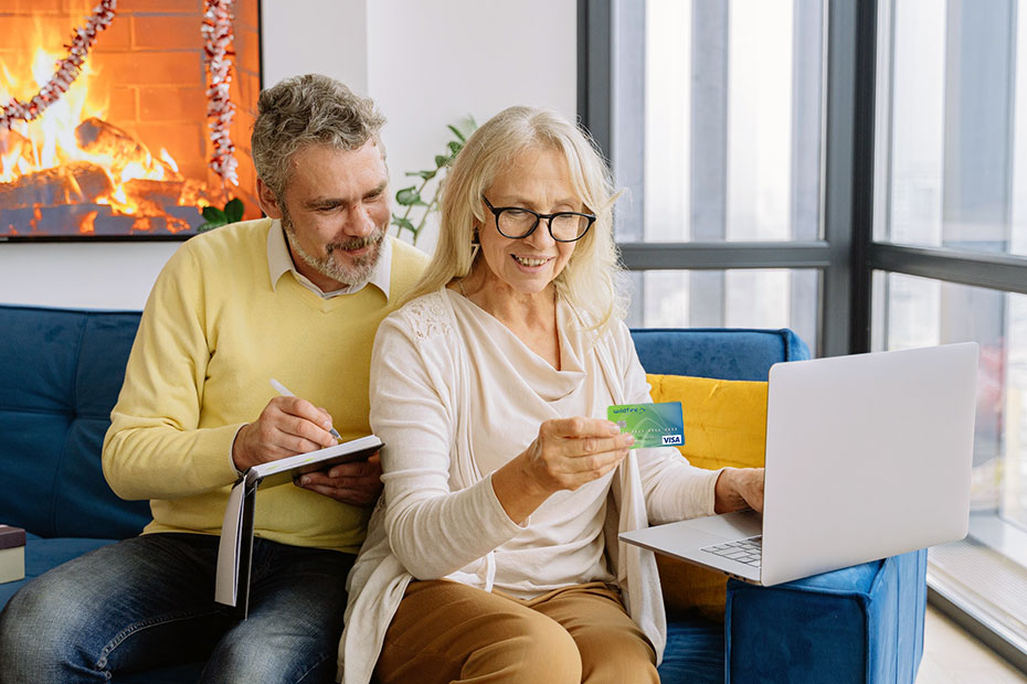 Elderly Couple happily looking at laptop and credit card