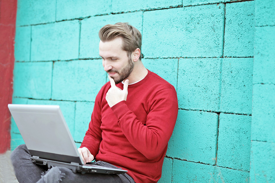 Happy adult male outside on laptop