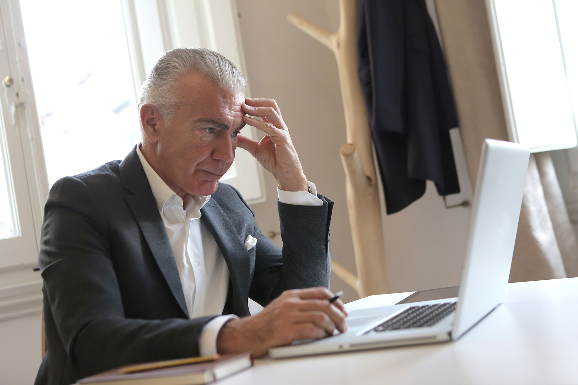 Man slightly stressed in Black Suit Jacket While Using Laptop