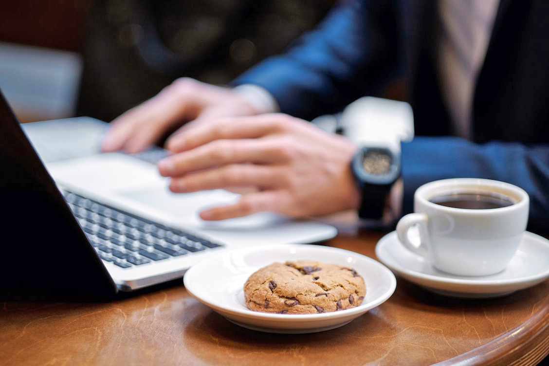 Person using laptop and eating a cookie