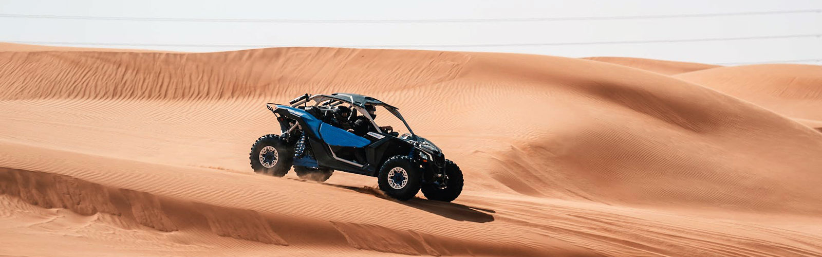 Blue Dune Buggy driving across sand dunes on a sunny day