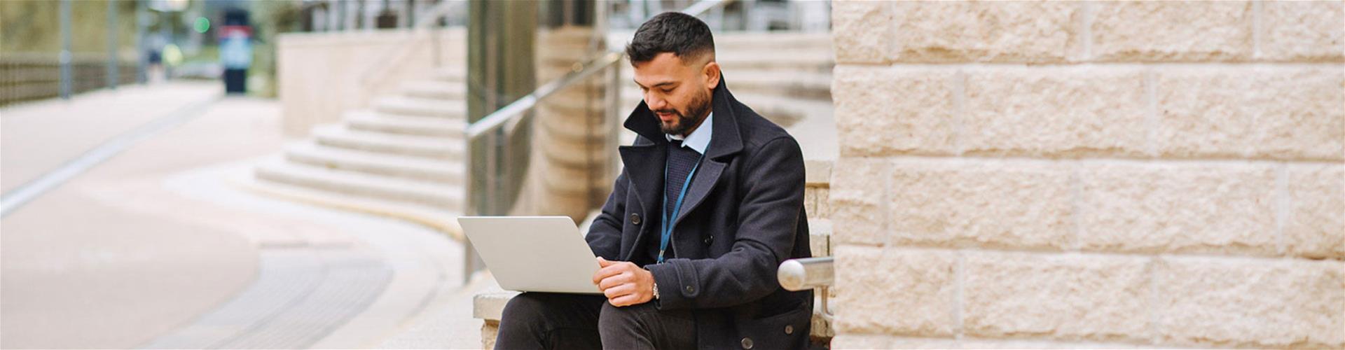 Businessman working on laptop outside on building stairs Businessman working on laptop outside on building stairs