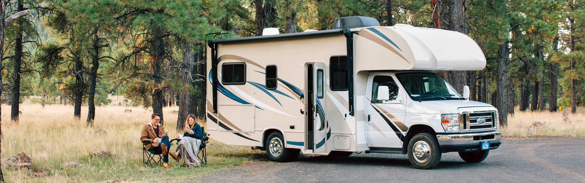 Couple sitting near RV at campsite during sunset