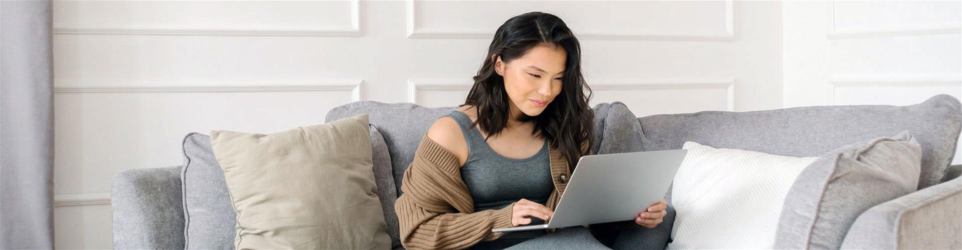 Female sitting on couch in living room using laptop Female sitting on couch in living room using laptop