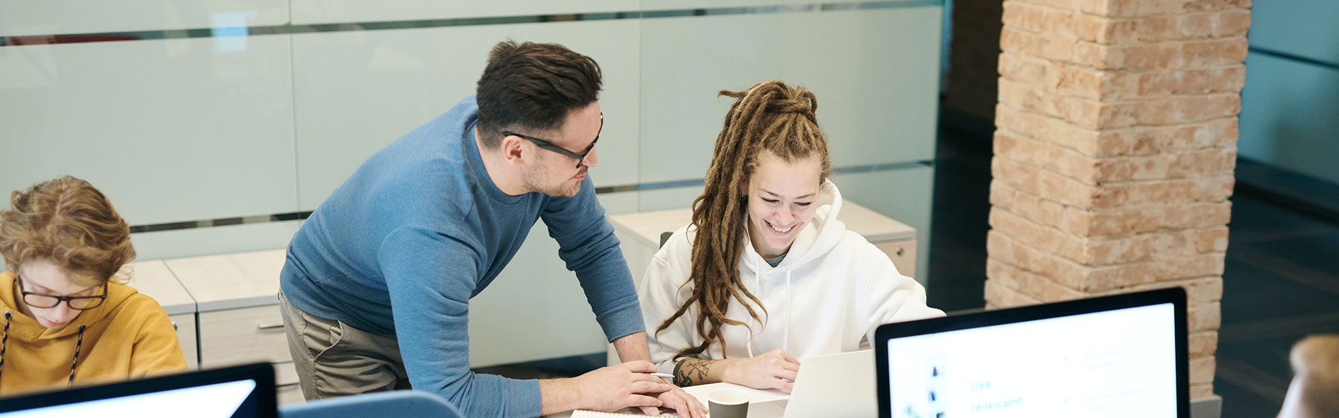 Man happily teaching woman about a computer Man happily teaching woman about a computer