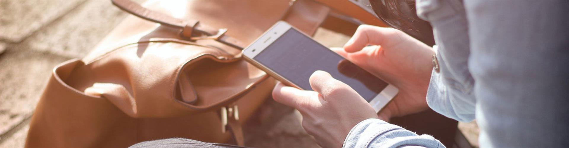 Person outside using smartphone while sitting down Person outside using smartphone while sitting down