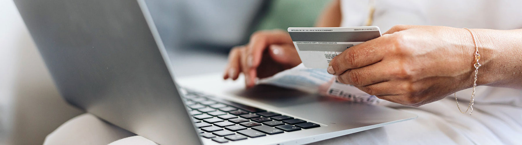 Person Using a laptop and Holding a debit card Person Using a laptop and Holding a debit card