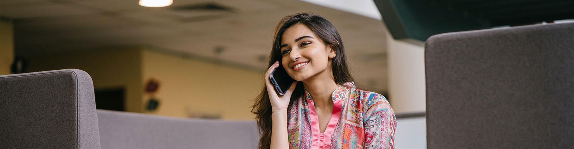 Smiling Woman in Floral Salwar Kameez Talking on Phone While Sitting