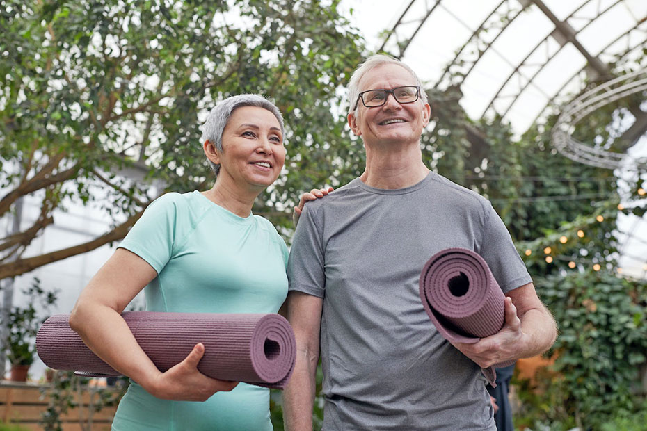 Confident retired couple holding yoga mays in a greenhouse.jpg Confident retired couple holding yoga mays in a greenhouse.jpg