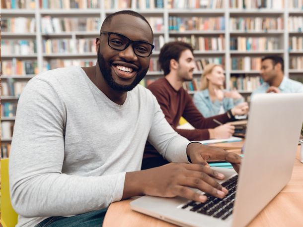 Gentleman smiling at laptop while in the library