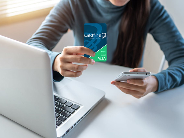 Woman on laptop and smartphone holding a Wildfire HSA Card Woman on laptop and smartphone holding a Wildfire HSA Card