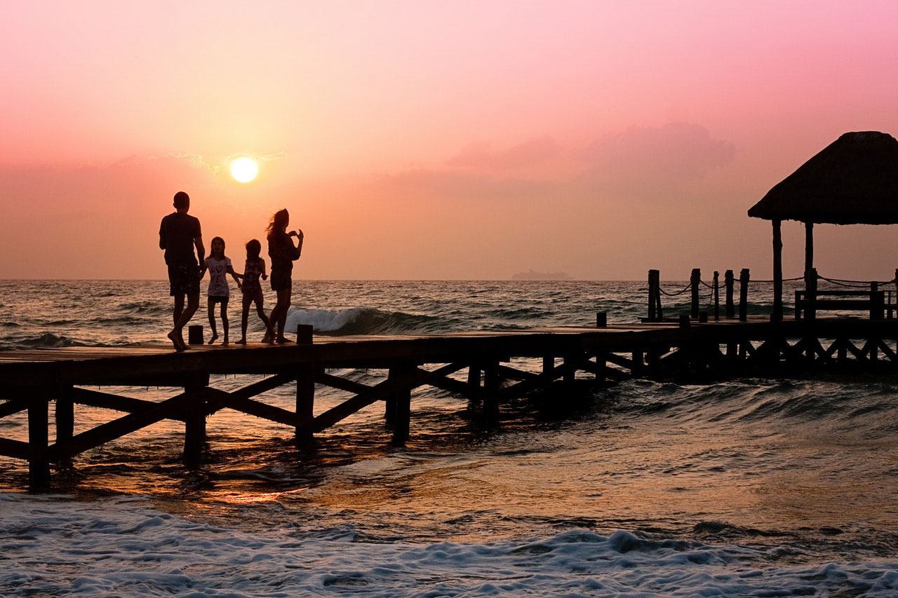 Family walking on dock on ocean during sunset