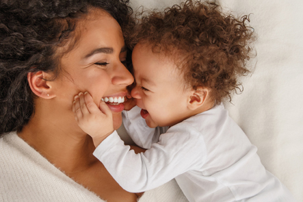 Happy mother and baby snuggling in bed