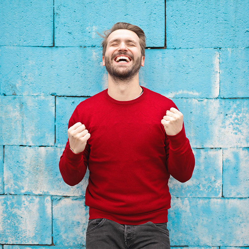 Man Rejoicing In Front of blue wall