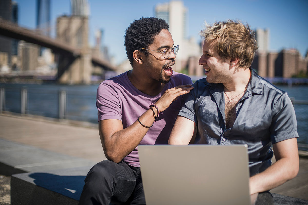 Men Smiling and Looking at Each Other while on a computer