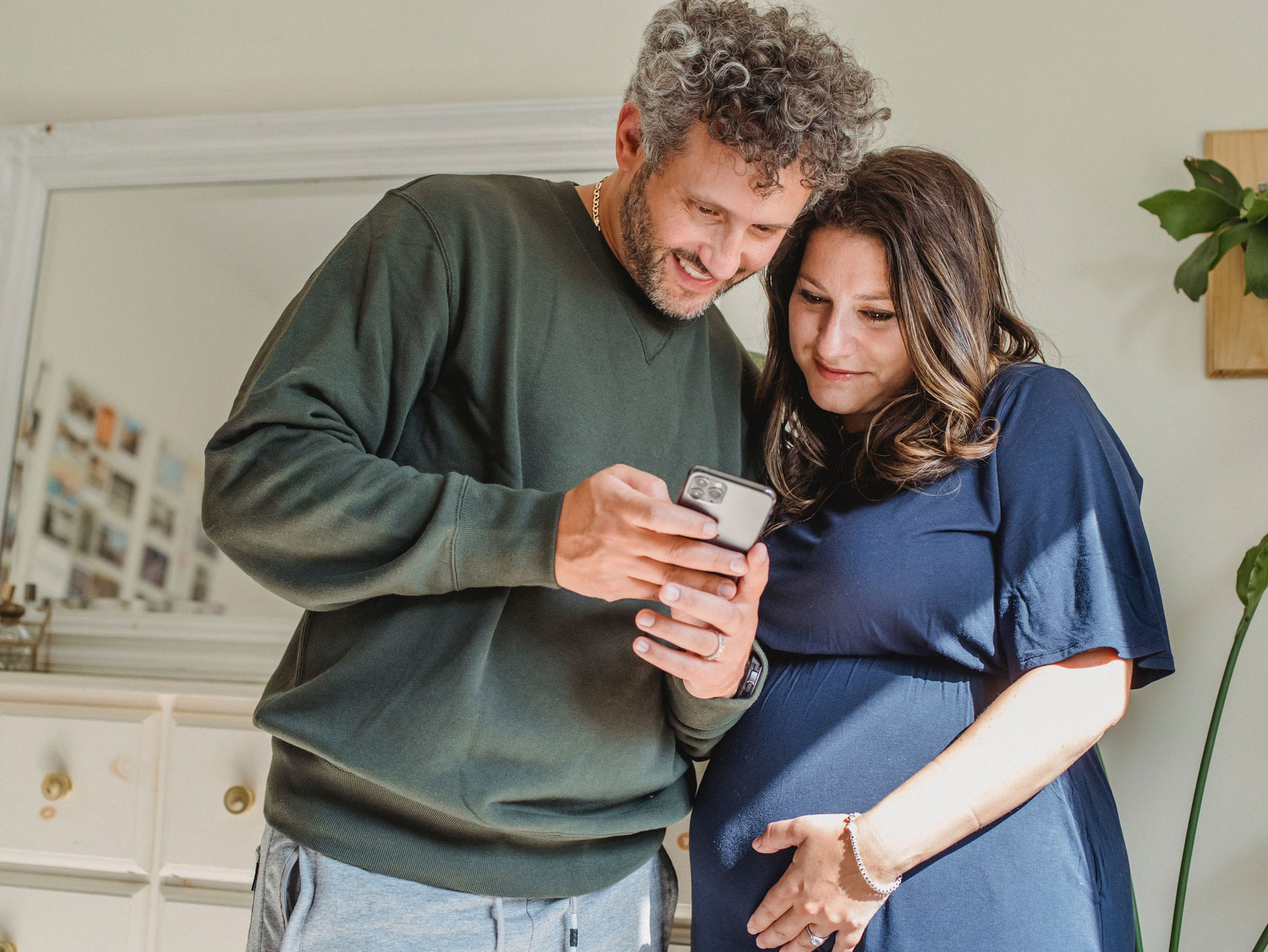 Adult man with pregnant wife watching smartphone at home Adult man with pregnant wife watching smartphone at home