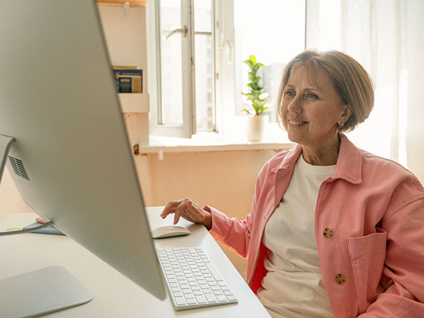 Senior Woman in Pink Button Up Shirt Using Desktop computer
