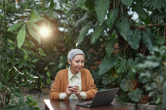 Woman Looking at Her Laptop in a greenhouse