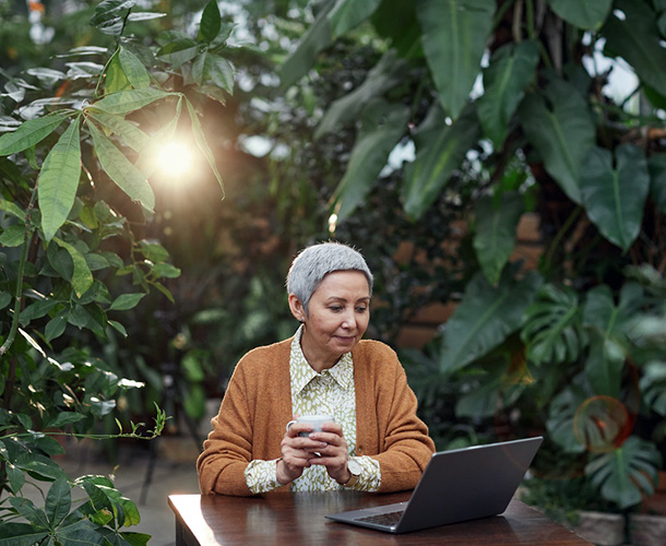 woman looking at laptop in greenhouse