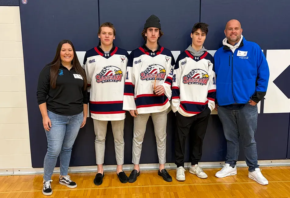 Wildfire employees taking a photo with three Saginaw Spirit hockey players.