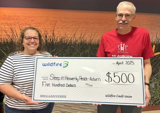 Wildfire employee and Sleep in Heavenly Peace of Auburn volunteer holding $500 check.