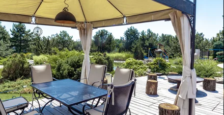Gazebo on back porch with chairs and table surrounded by trees