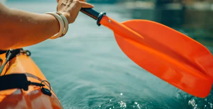 Edge of canoe and paddle gliding through a river