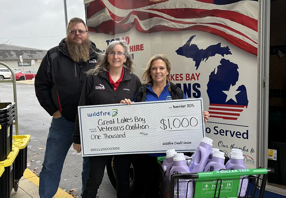 Wildfire employee holding $1,000 check in front of trailer with two GLBVC employees and supplies.