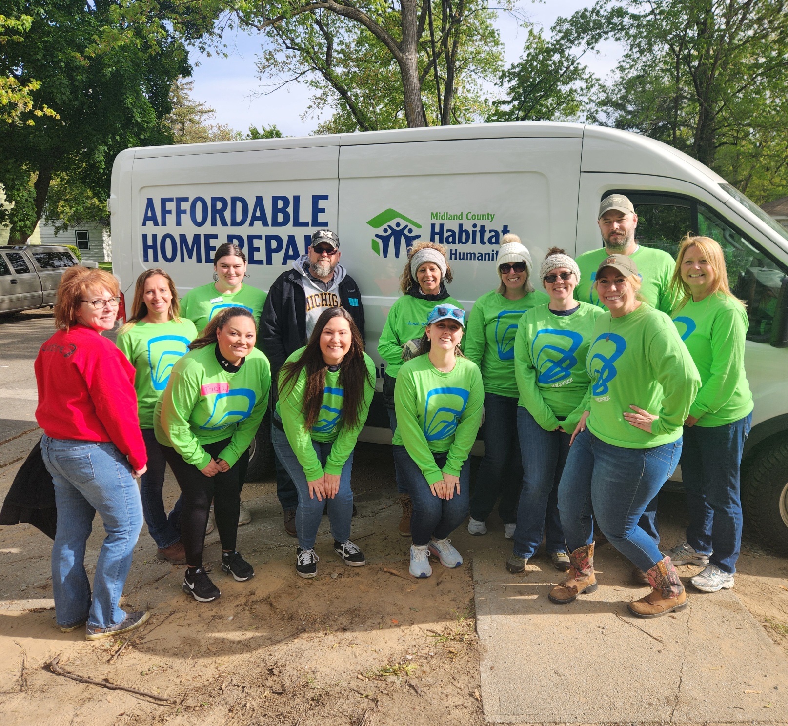 Wildfire team in green shirts in front of Habitat for Humanity van all smiling.