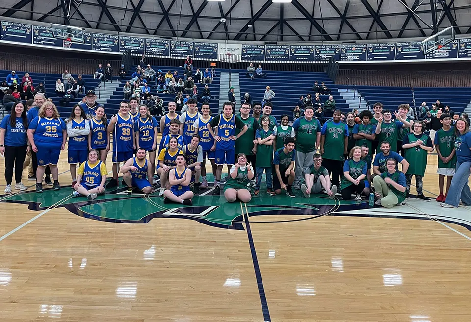 Heritage Hawks and Midland Chemics team taking picture together in gym after basketball game.