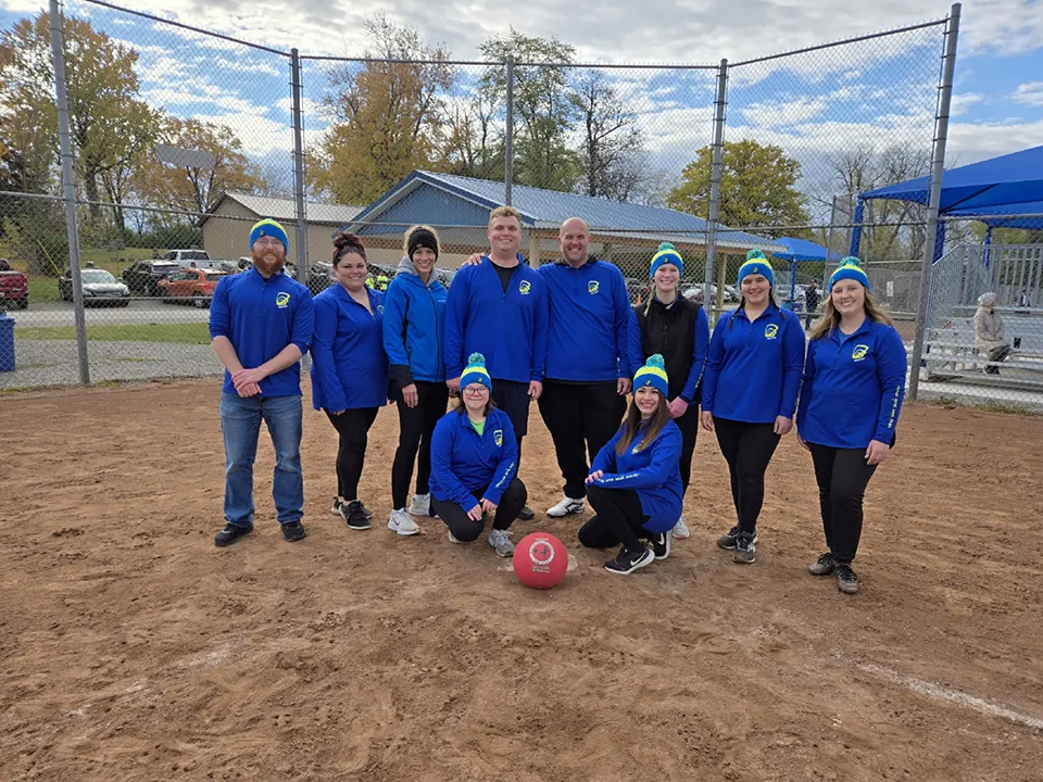 Wildfire employees at home base taking picture next to kickball wearing blue Wildfire jackets.