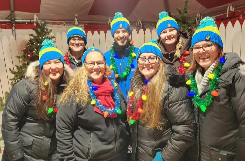 Wildfire team with same color hats smiling inside tent at Christmas in Kochville Township.