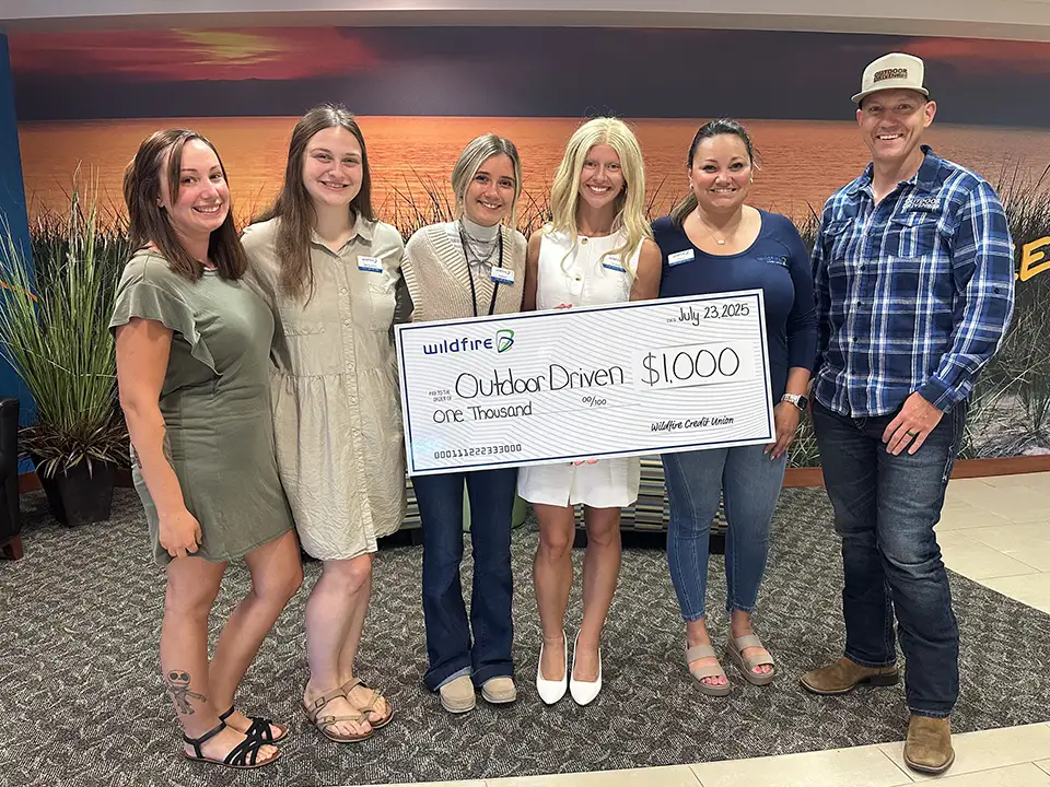 Wildfire employees in branch present check to Outdoor Driven.
