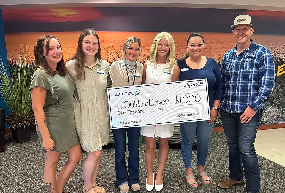 Wildfire employees in branch present check to Outdoor Driven.