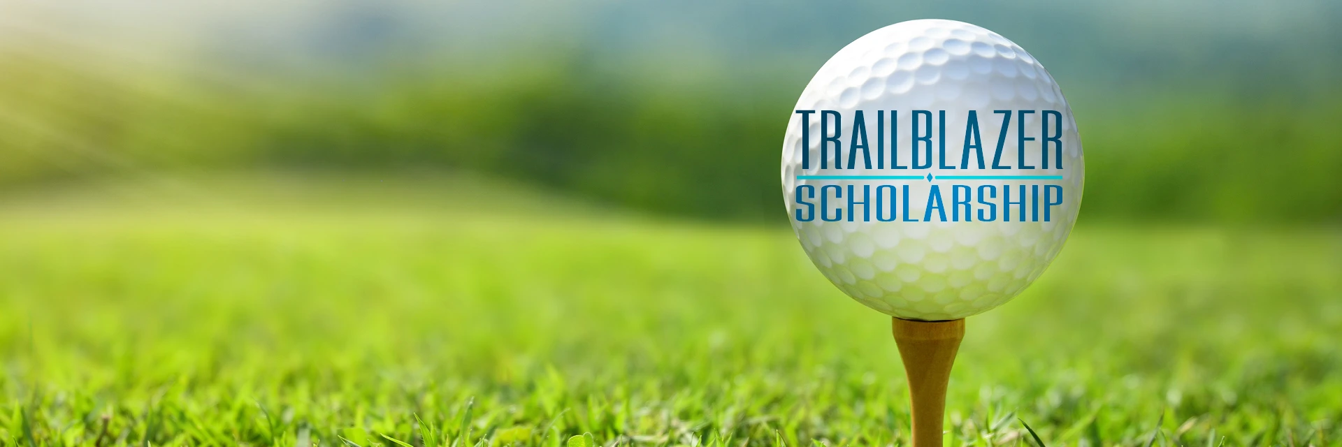 Green grass on a sunny day with a golf ball on a tee that has text of Trailblazer Scholarship.