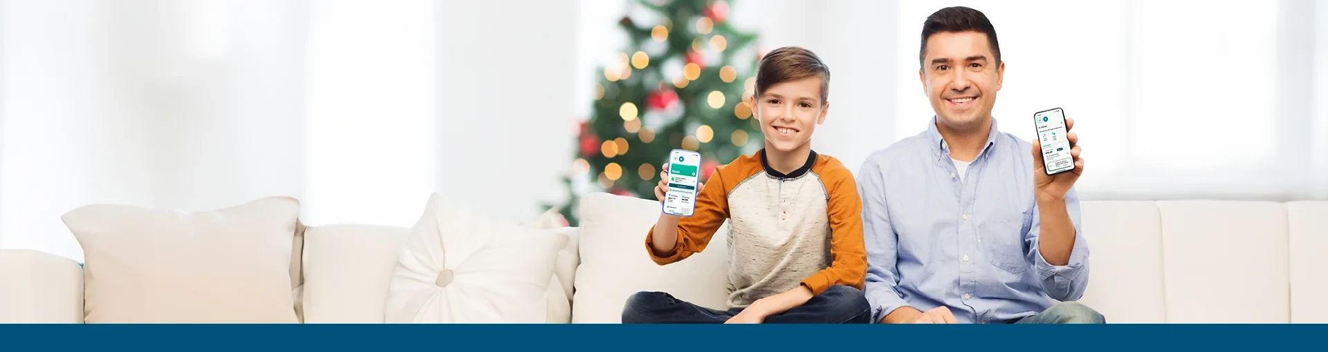 Father and son sitting on couch with the Greenlight app on cell phones with tree in background.
