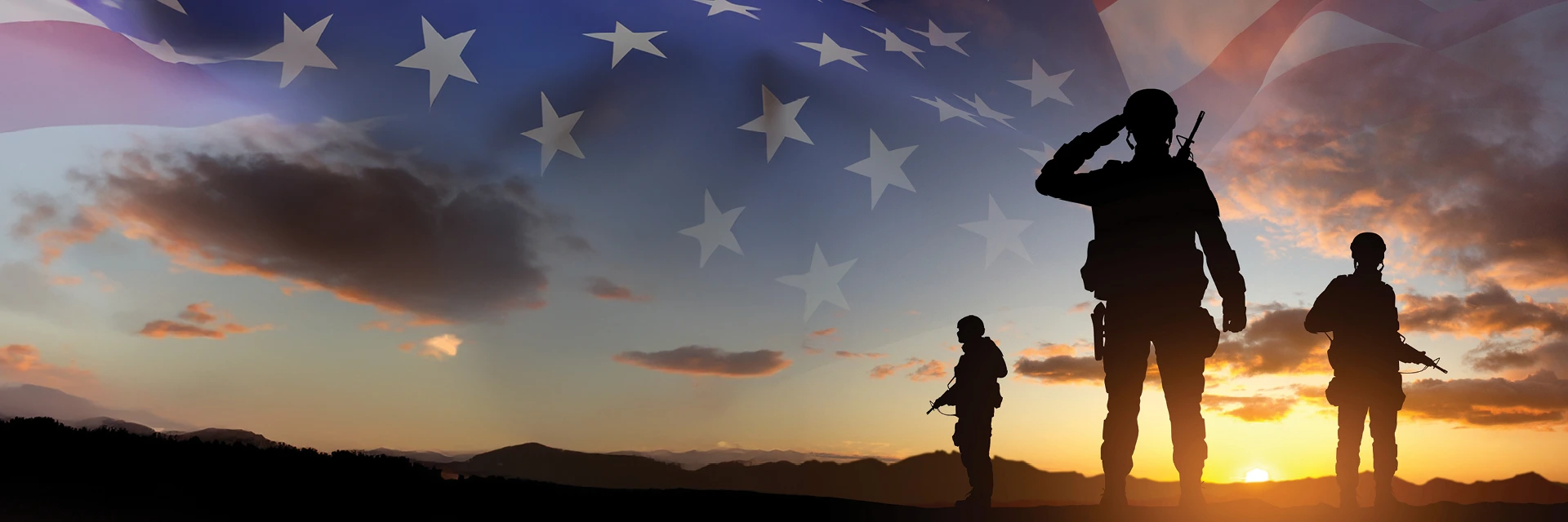 Group of three soldiers standing with a sunset and american flag on the horizon.