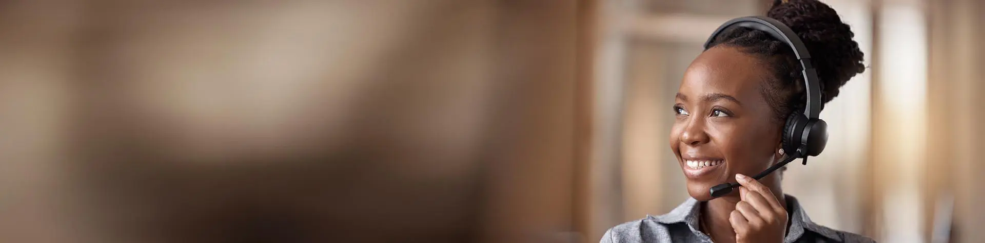 Smiling female customer service representative wearing a headset in a contact center.