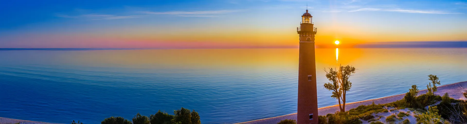 Aerial view of Michigan lighthouse at sunset over the Great Lakes.