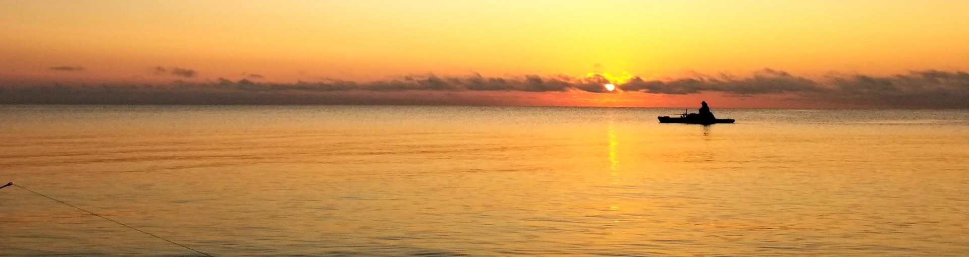Fisherman in kayak on a calm Lake Michigan at sunset.