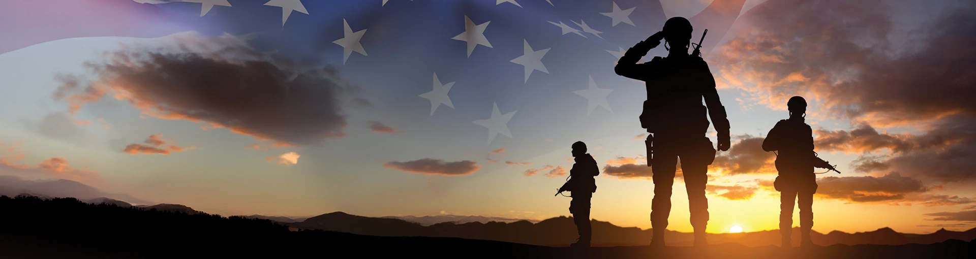 Group of three soldiers standing with a sunset and american flag on the horizon.