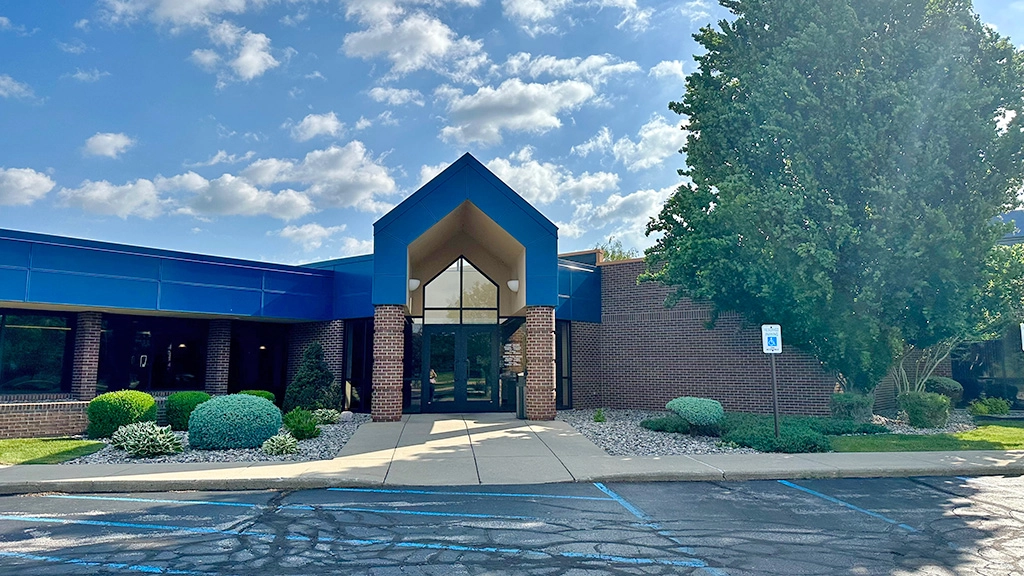 Main office entrance on a blue sunny sky day during summer with green landscaping.