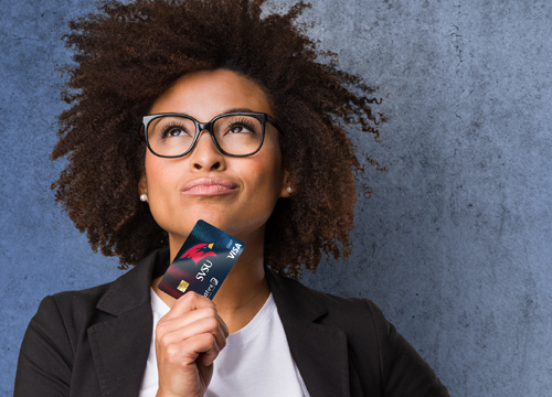 Businesswoman looking up confidently holding a Wildfire debit card