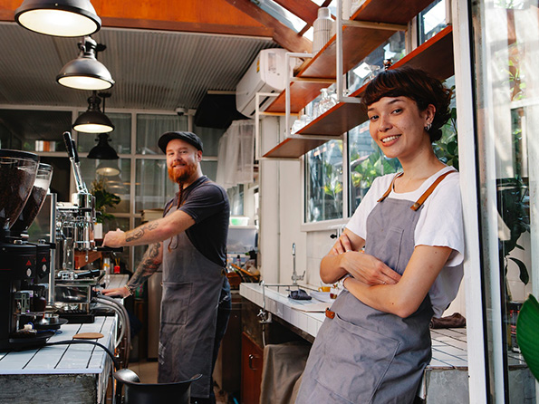 confident male and female shop owners making coffee