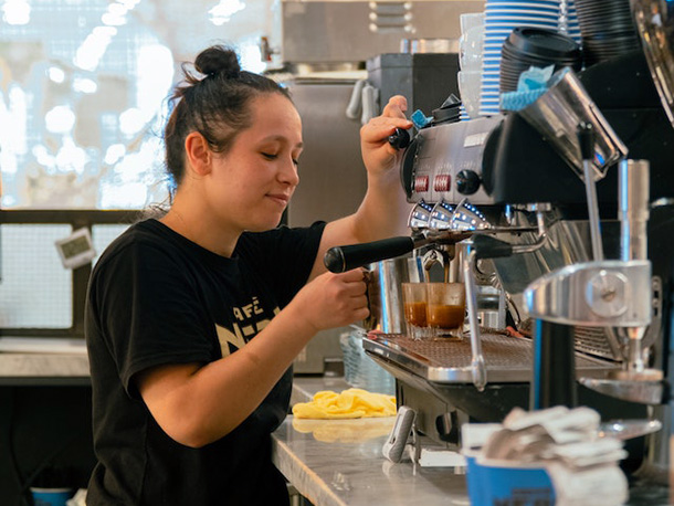 Happy female working with espresso machine