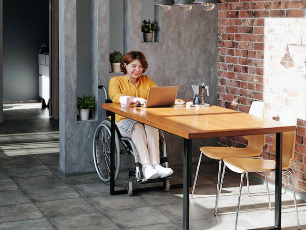woman in wheelchair using laptop in office woman in wheelchair using laptop in office