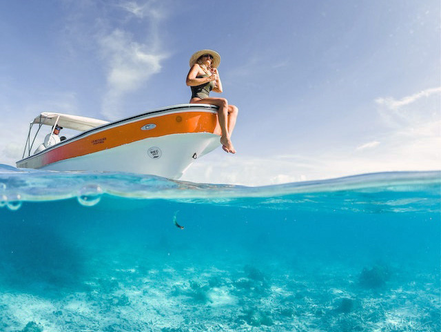 woman sitting on edge of boat in lake